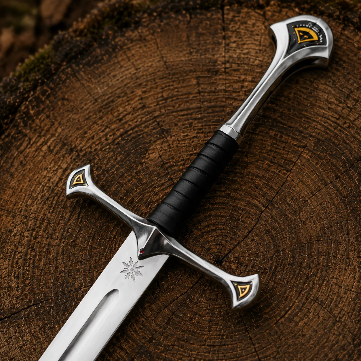 Close-up Anduril sword hilt with black wrapped grip, sweeping silver-coloured guard, pommel and gold accent details