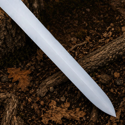 Detailed close-up of the satin-finish stainless steel Power Sword blade and tapered point over a woodland floor