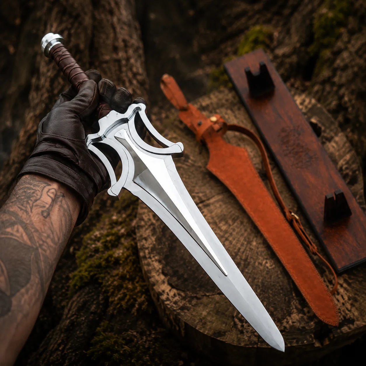 Gloved collector holding the silver He-Man Power Sword above a woodland stump with sheath and plaque behind