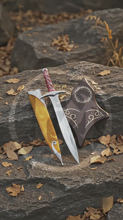 Product video showing the High Elven Warrior Sword replica with its engraved silver blade, red grip, brown scabbard and decorative Elven wall plaque in an outdoor woodland setting.