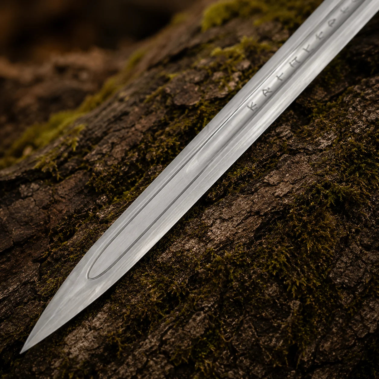 Close-up of the Ragnar Lothbrok Viking sword blade showing rune-style engravings, central fuller and pointed tip