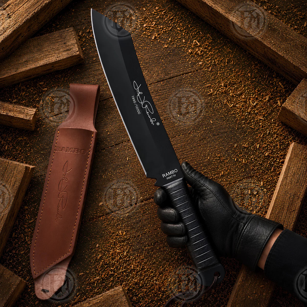 Hand-held Rambo IV movie machete showing black blade, signature numbering and brown leather sheath on rustic wood.