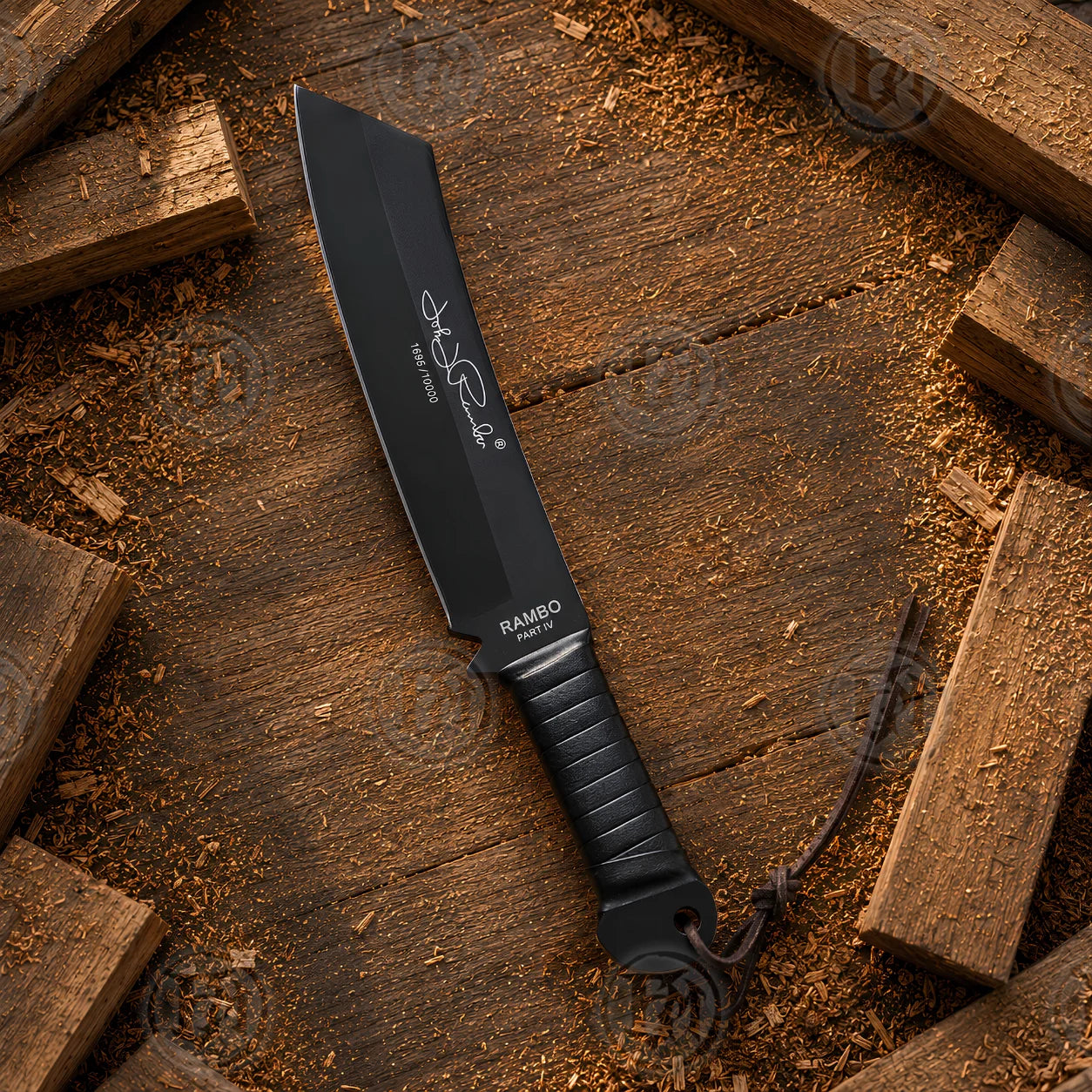 Full-length Rambo IV movie machete displayed on rustic timber with black blade, signature detailing and lanyard.