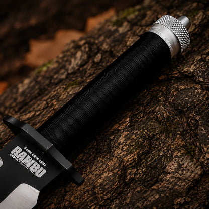 Close-up of the Rambo knife handle showing black cord wrapping, metal pommel and printed movie detailing